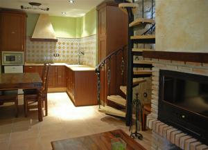 eine Küche mit einem Wohnzimmer mit einem Kamin und einem Tisch in der Unterkunft La Azacaya in Baeza