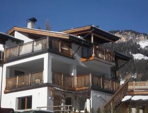 un gran edificio blanco con balcones de madera. en casa Lory en Vigo di Fassa