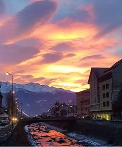 una puesta de sol sobre una ciudad con un río y edificios en Albergo Gusmeroli, en Tirano