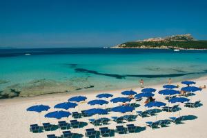 un grupo de sombrillas y sillas azules en una playa en Splendido mono vista mare con wi fi a 100 mt da spiaggia, en Santa Teresa Gallura