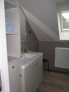 a white bathroom with a sink and a window at au-magasin in Vielsalm