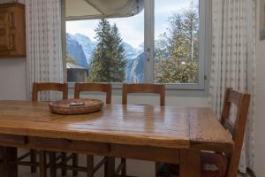 une table à manger avec des chaises et une grande fenêtre dans l'établissement Apartment Belvedere, à Wengen
