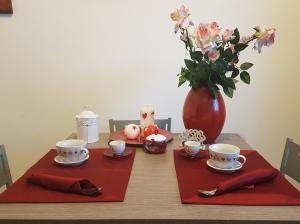カターニアにあるCatania Suite Homeの赤いナプキン2本と花瓶1本のテーブル