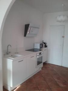 a white kitchen with a sink and a microwave at Petite Fleur d'Azur in Cagnes-sur-Mer