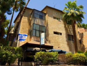 un edificio con una señal delante de él en A Little House In Rechavia, en Jerusalén