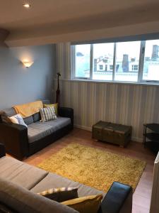 een woonkamer met een bank en een groot raam bij Apartment 5, Cornerhouse Apartments in Llandudno