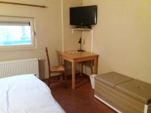 a bedroom with a bed and a desk with a television at B&B Euverbraeke in Beveren