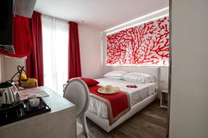 a bedroom with a bed with a red painting on the wall at Il Mare Dentro Rooms in San Vito lo Capo