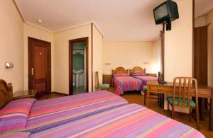1 dormitorio con 2 camas, mesa y TV en Hostal Hispano, en Nájera