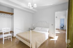 Un dormitorio blanco con una cama y una silla. en Domus Citri, en Caserta