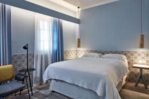 a bedroom with a white bed and a chair at Angelina Boutique Escape in Perdika