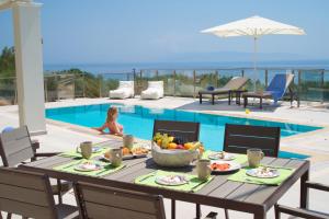 - une table avec un bol de fruits à côté de la piscine dans l'établissement Villa Ion Pangea Villas, à Trapezaki