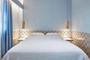 a bedroom with a large white bed with two lights at Angelina Boutique Escape in Perdika
