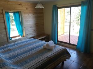a bedroom with a bed with blue curtains and a deck at Cabañas Rincon del Sur in Cochrane