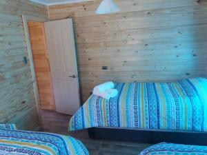 a bedroom with two beds and a white door at Cabañas Rincon del Sur in Cochrane