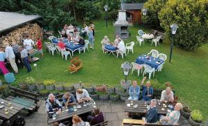 a group of people sitting at tables in a garden at Haus zur Sonne Sauerland in Hallenberg