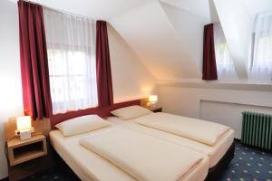 2 łóżka w małym pokoju z czerwonymi zasłonami w obiekcie Pension Alter Wirt w mieście Enkering