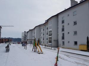 an empty playground in the snow next to a building at Apartament-Studio Polana Szaflarska in Nowy Targ