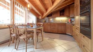 una cocina con armarios de madera, mesa y sillas en Alpenblick Superior en Zermatt