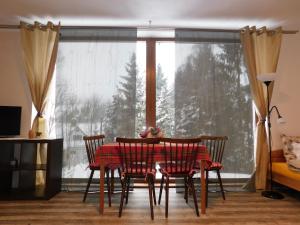 a dining room table and chairs in front of a window at Apartmány Kunc in Bedřichov