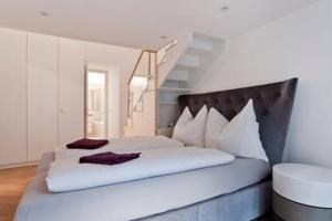 ein Schlafzimmer mit einem Bett mit weißer Bettwäsche und einer Treppe in der Unterkunft Homestay Sisi in Wien