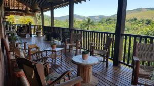 a porch with chairs and tables and a view of the mountains at Ibiti Hotel Rural in Monte Alegre do Sul