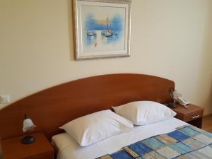 a bed with two pillows and a picture on the wall at Apartments Silvana in Trogir