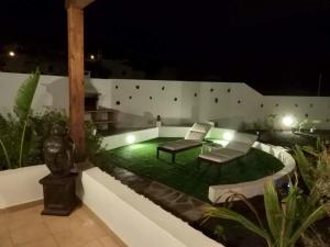 a patio with two chairs and a table at night at Finca La Costa in Tinajo