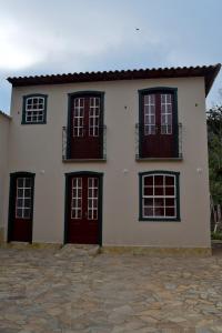 a white house with red doors and windows at Solar de Amelia in Tiradentes