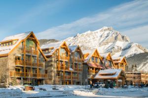 a large lodge with snow covered mountains in the background at Moose Hotel and Suites in Banff