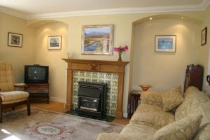 un soggiorno con camino e divano di Woodcroft Cottage ad Ayr
