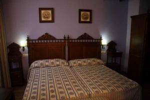 Hotel El Maño في هويسكار: غرفة نوم بسرير كبير وصورتين على الحائط