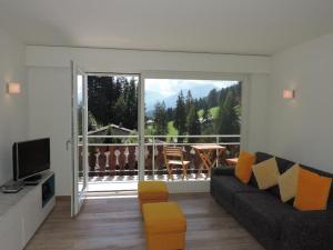 a living room with a couch and a television and a balcony at Damiez (171 Zi) in Lenzerheide