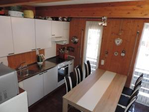 una cocina con armarios blancos y una mesa y sillas de madera. en Las Bargias 8 (472 Me), en Lenzerheide