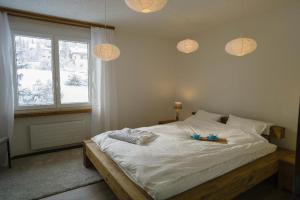 a bedroom with a bed with white sheets and a window at Seestrasse 1 (292Ap) in Lenzerheide