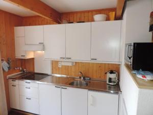 una cocina con armarios blancos y fregadero en Las Bargias 9 (457 Bo), en Lenzerheide