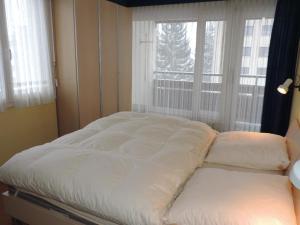 Cette chambre comprend un grand lit et une fenêtre. dans l'établissement Ladina 74 (363 Ko), à Lenzerheide