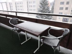 uma mesa e uma cadeira numa varanda coberta de neve em Ladina 74 (363 Ko) em Lenzerheide