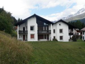 a white house with a black roof on a green field at Gloria C4 (276 Rc) in Lenzerheide