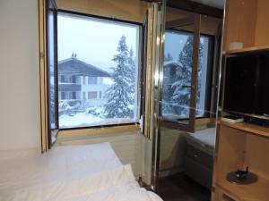 a bedroom with a bed and a large window with snow at Sil Bot (3000 Bw) in Lenzerheide