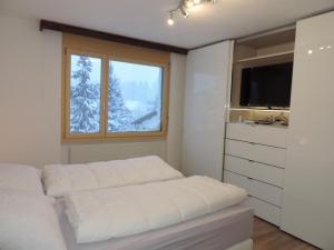 a white bedroom with a bed and a window at Sil Bot (3000 Bw) in Lenzerheide