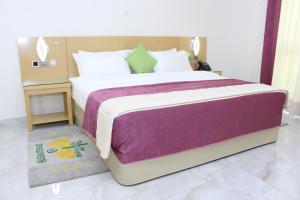 a bedroom with a large bed with a purple blanket at Paradisia Hotel in Cotonou