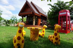 a group of giraffe sculptures in front of a phone booth at Ruean Phet Sawoei Resort in Phutthaisong