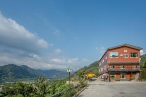 a building on a hill with mountains in the background at Bai Shengcun Homestay in Guoxing