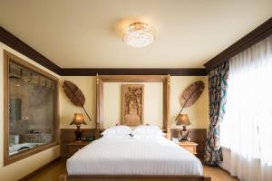 a bedroom with a white bed and a window at Peak Nimman Prestige Hotel in Chiang Mai