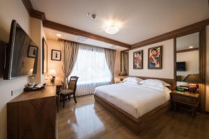a bedroom with a bed and a desk and a television at Peak Nimman Prestige Hotel in Chiang Mai