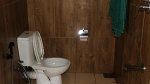 a bathroom with a toilet in a wooden wall at Birds Paradise Hotel in Kudawe