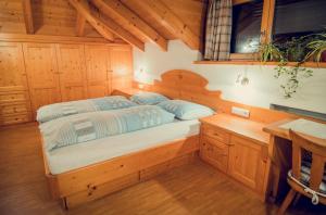 ein Schlafzimmer mit einem Bett in einem Holzzimmer in der Unterkunft Appartements Tlusel in St. Ulrich in Gröden