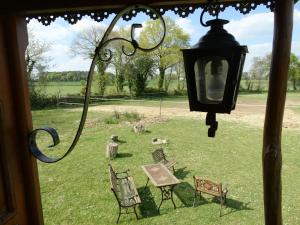 vistas a un patio con sillas y una lámpara en Une roulotte et des chevaux, en Sulniac