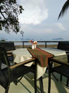 a table with two chairs and a vase of flowers on it at Mookdaman Bungalow in Ko Yao Noi